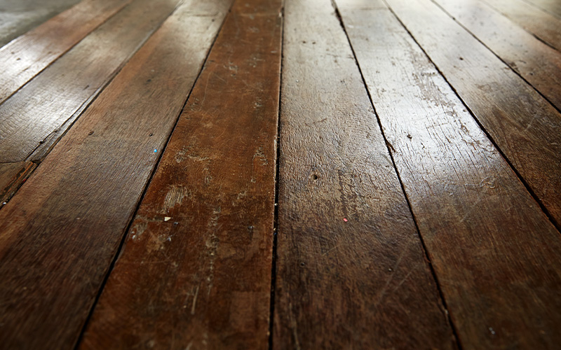 Close-up of rustic scratched and worn brown wooden flooring.